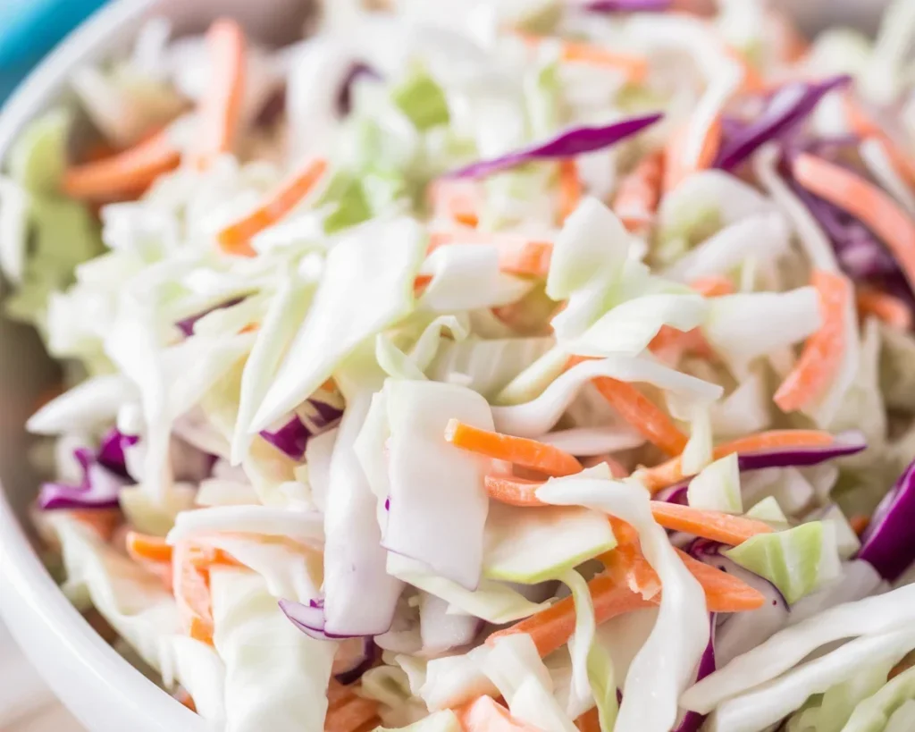 Bowl of easy coleslaw with green cabbage and carrots covered in creamy dressing.